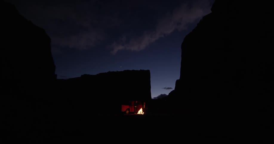 A man is walking around near a campfire at night
