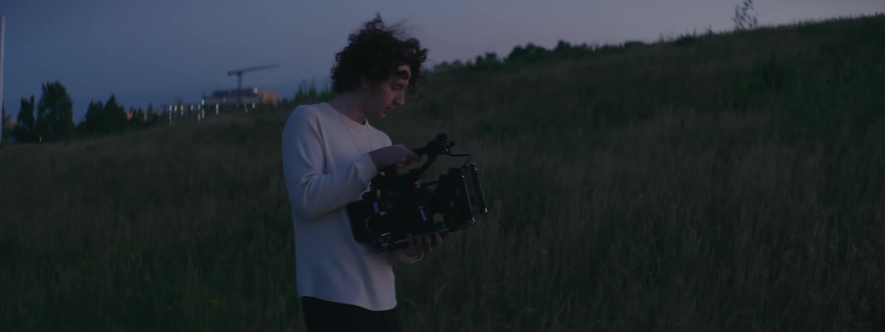 A man records video while standing on a hill