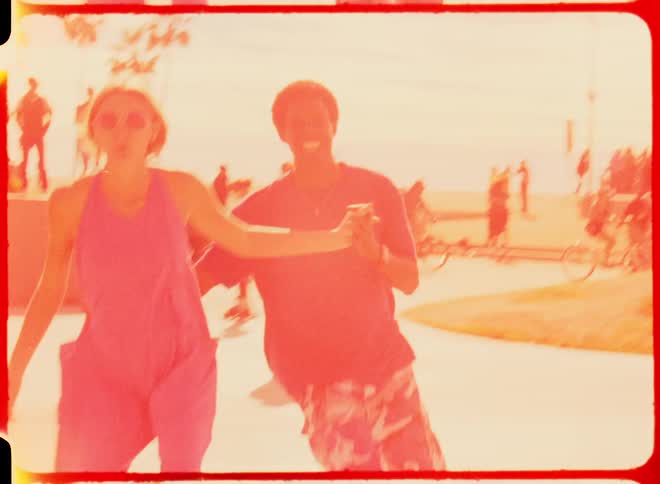 A man and woman hold hands while roller skating outdoors during the day
