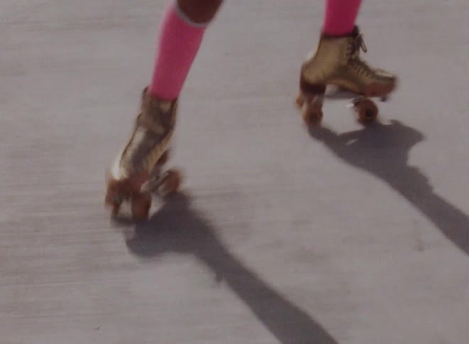 Female skater wearing hot pink socks dances and casts shadow on ground