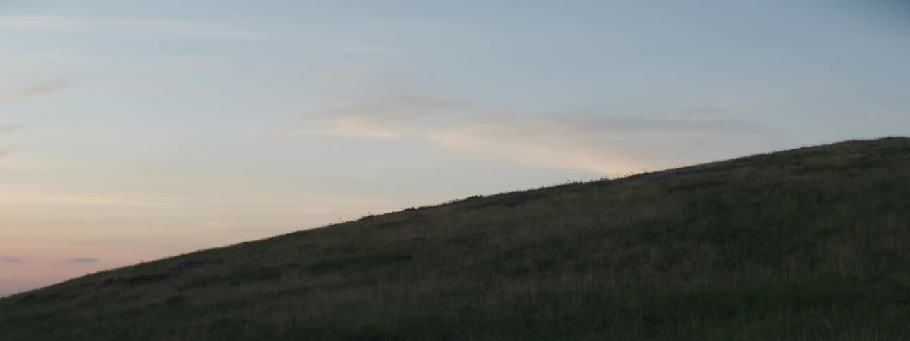 Grass covered hillside and a few clouds in the sky