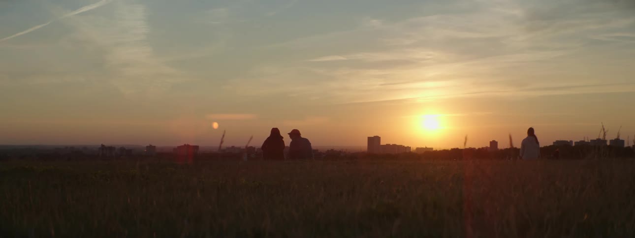 A group of people chat while sitting in an open field