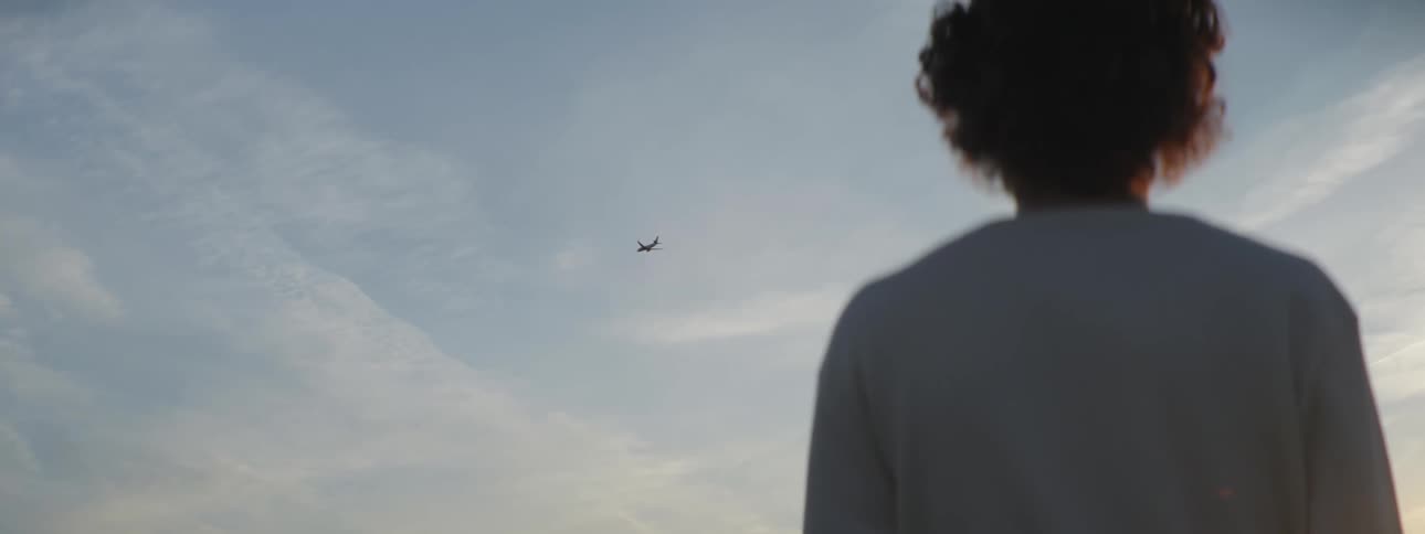 A person is watching a plane fly in the sky