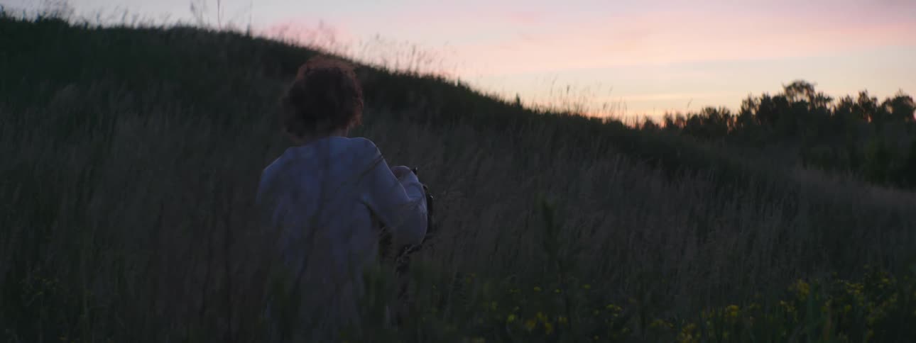 A person uses a video camera to film a hillside in the evening