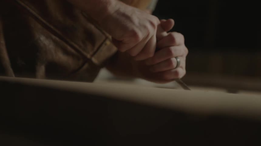 A man is shaving wood with a tool