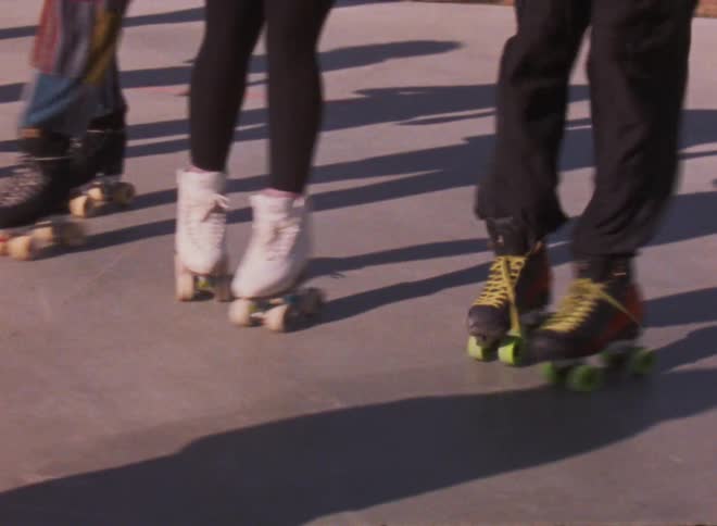 A group of friends roller skate in unison in a park