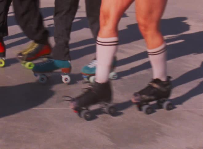 A group of skaters perform a synchronized dance on roller skates outdoors during the day