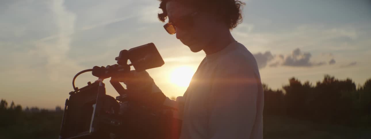 A man records video in the forest with a large professional camera