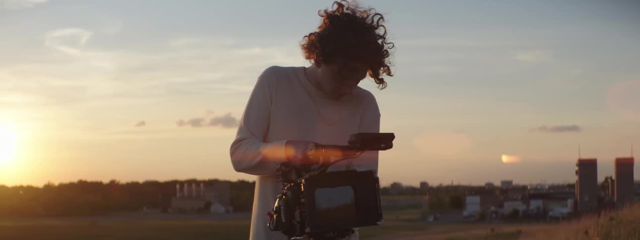 A man records video on a hill with views of downtown