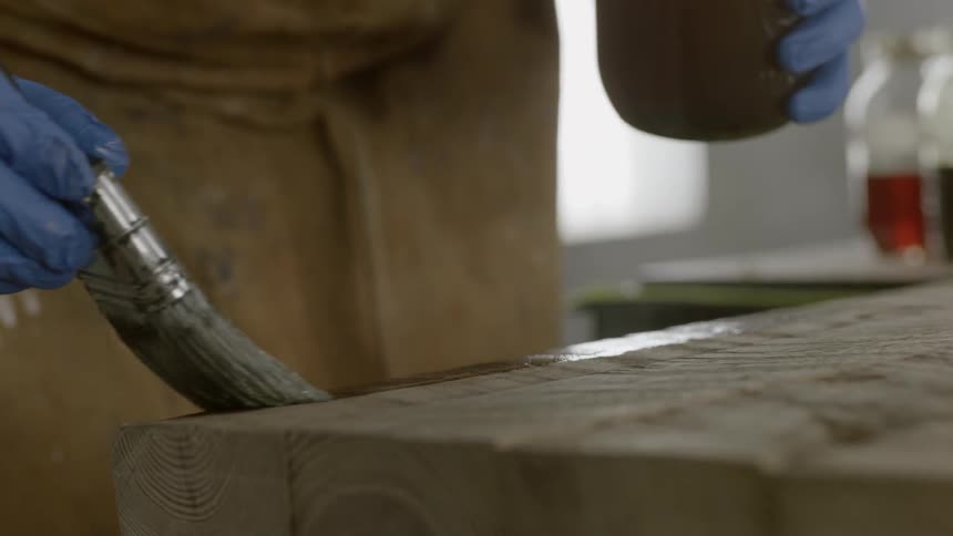 A person stains a wood table