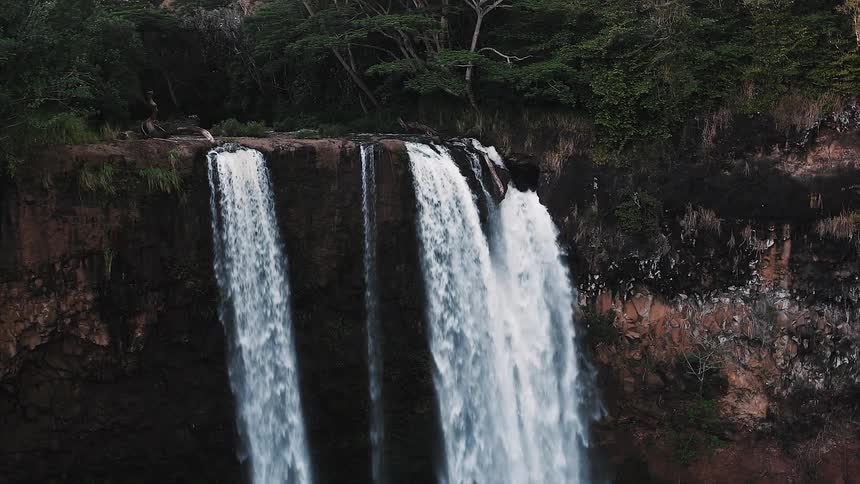 A waterfall flows over a cliff edge in a jungle