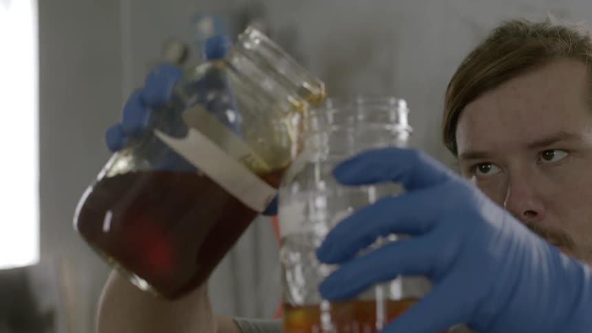 Man pouring a liquid from one jar to another