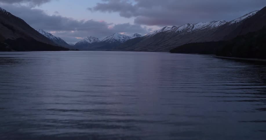 Gently rippling body of water surrounded by snow-capped mountains