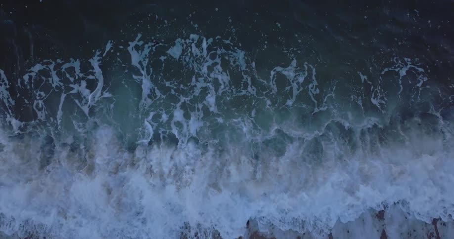 Ocean waves curl and break splashing and foaming on shore