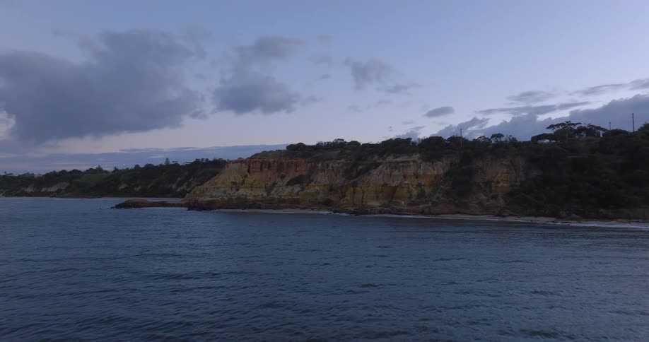 Narrow strip of sandy beach separates cliff from ocean