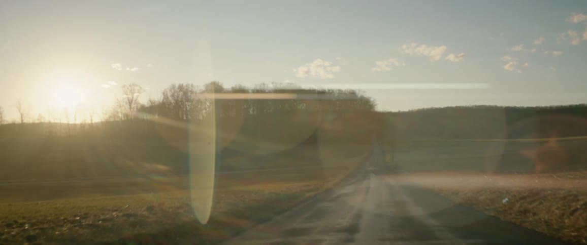 Sunset flares over the hills near a rural country road in the countryside