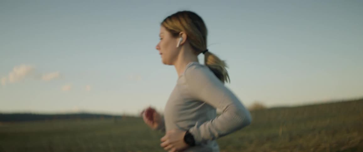 A woman jogs along a road through the countryside during the day