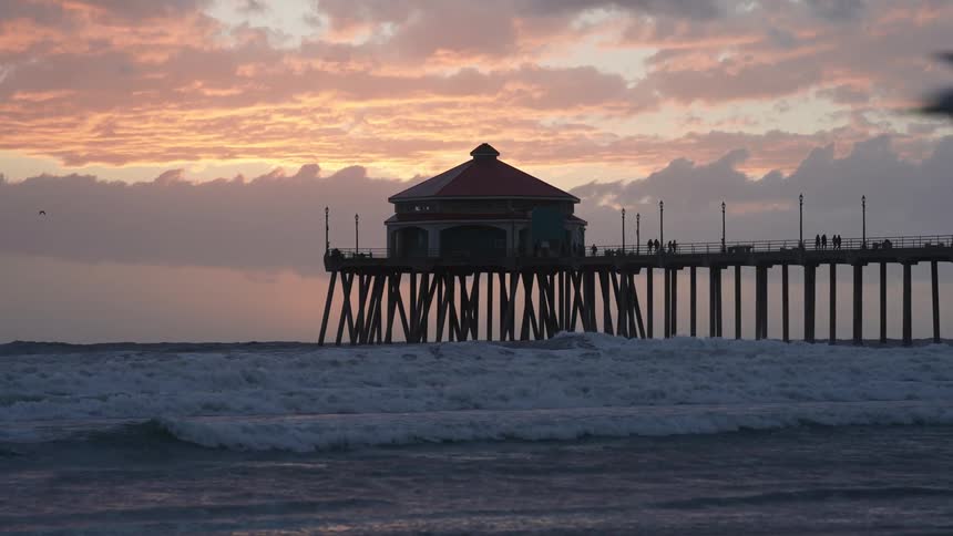 A building at the end of a boardwalk over the ocean on a cloudy evening