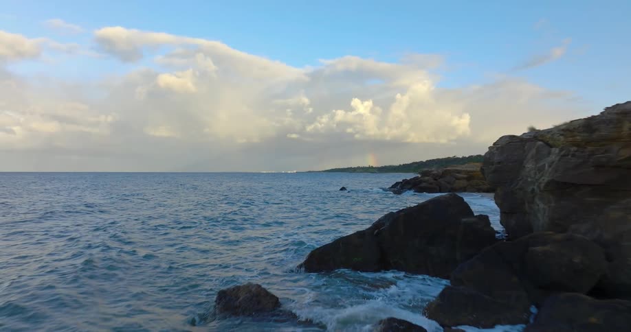 Ocean waves splash against a rocky shore and sandy beach