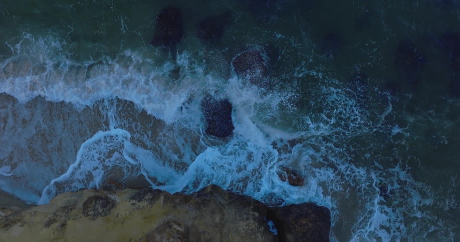 Ocean waves splash and foam against the rocky shore