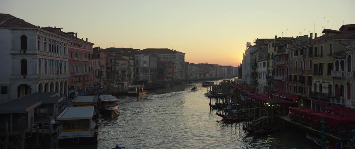 Boats round a bend in the Grand Canal in Venice, Italy at sunset