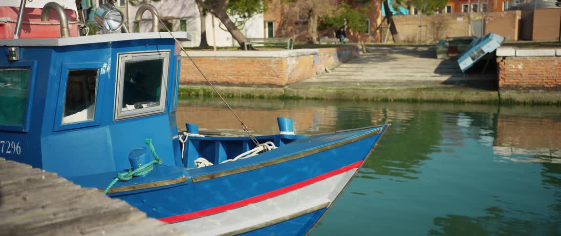 A colorful fishing boat docked along the channel on Burano Island, Venice, Italy