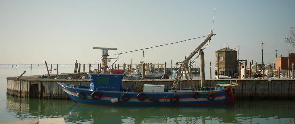 Colorful fishing boat docked along with other boats on the pier on Burano Island, Venice, Italy