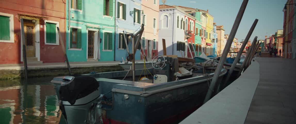 Boats line a canal flanked by colorful homes on Burano Island in the Venetian lagoon, Italy