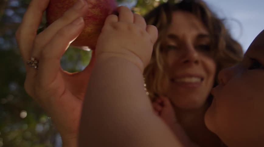 A mother shows her son a piece of hanging fruit