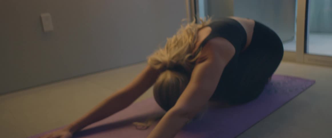 A woman stretches on the floor of her living room