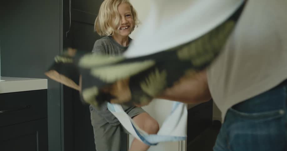 A boy and his father jokingly whip towels at each other