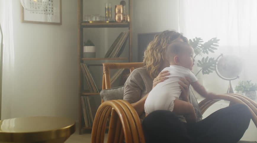 Mom sitting in a chair cross legged holding her baby and kissing his face