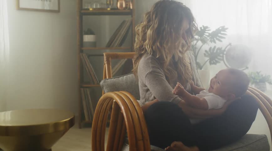 Mother smiles while holding baby in her lap