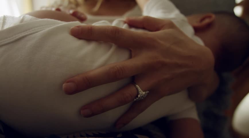 A woman cradles a baby while sitting indoors during the day