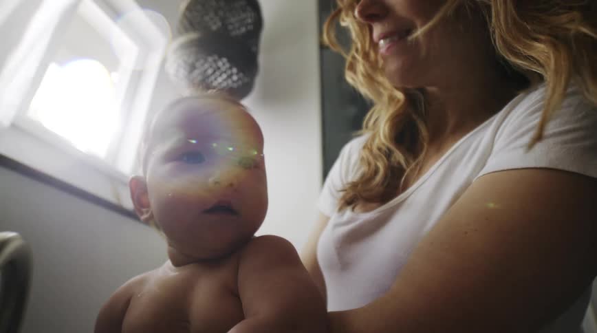 Mother laughs as child splashes in water coming from faucet