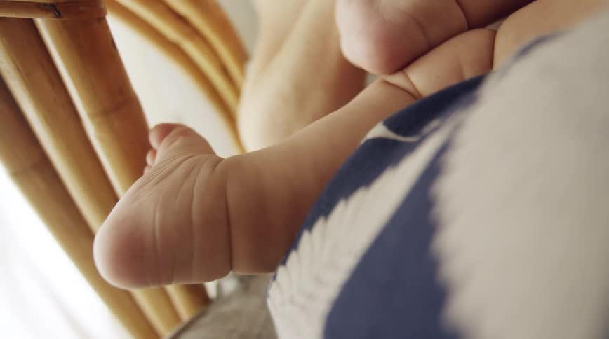 A baby lies on a cushion on a wicker chair