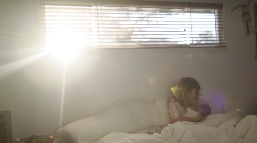A woman breastfeeds her baby while lying in bed