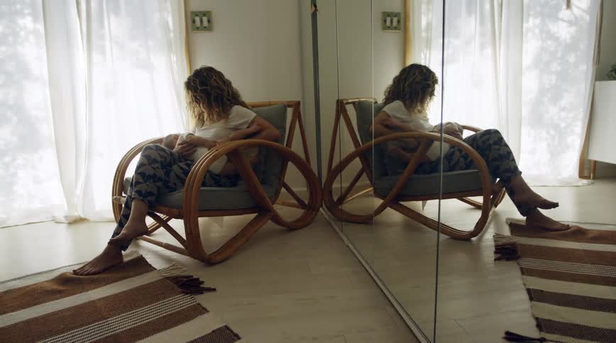 A woman sits at home and holds her baby