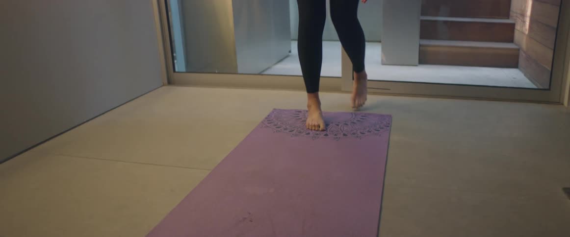 Blonde woman with black sports bra and leggings does yoga on purple yoga mat
