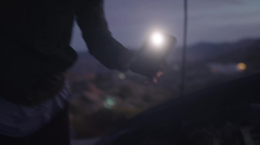 A man is working on his engine using his phone as a flashlight