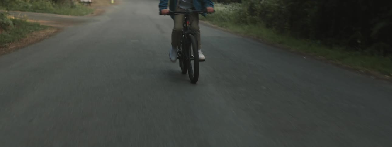 A person rides a bicycle up a road during the day