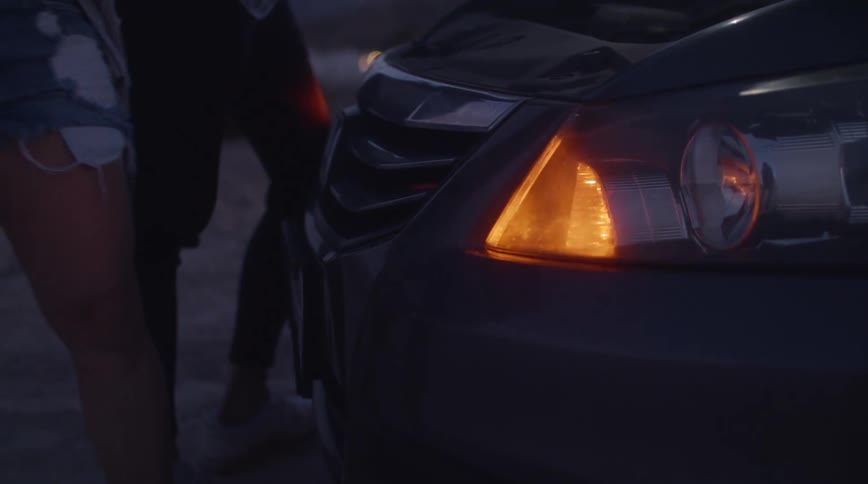 People stand near front of car on roadside as the lights on vehicle flash