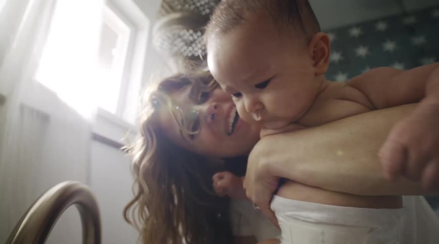 A mother is putting her baby in the tub