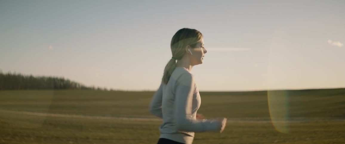Woman with ponytail gray sweatshirt and black leggings runs in the countryside