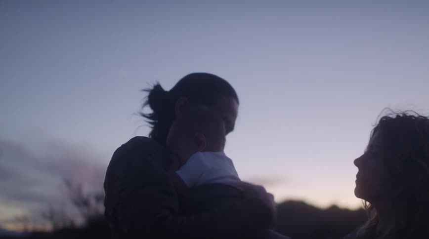A father rocks his baby near a car breakdown