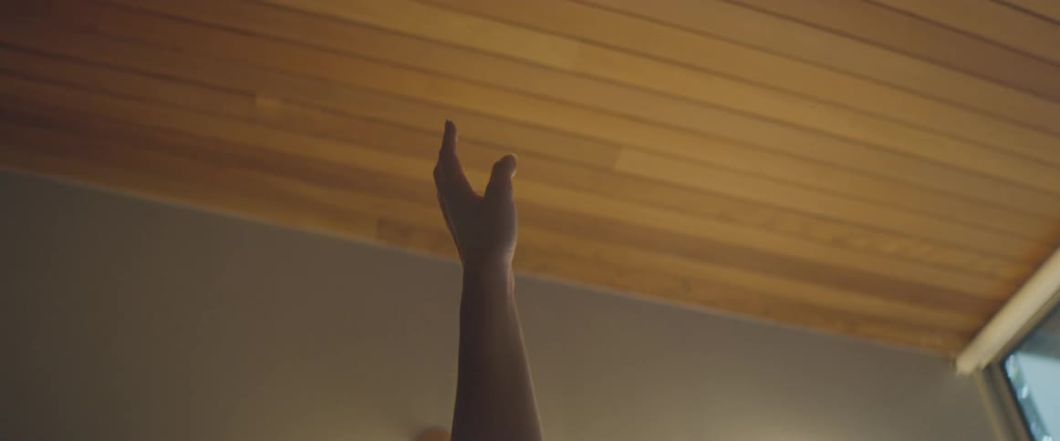 A woman moves her upper body downwards in a yoga stretch extending one arm up toward the ceiling