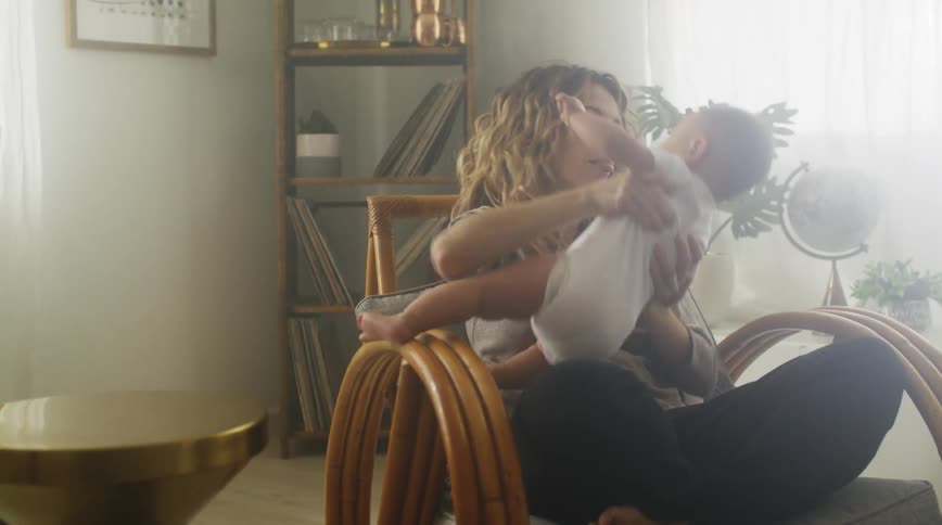 Mom sitting in a chair cross legged holding her baby