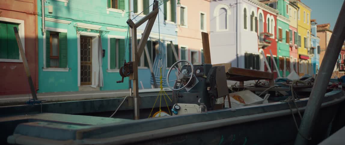 Close up of a boat docked in canal with colorful homes surrounding on Isola di Burano, Venice, Italy