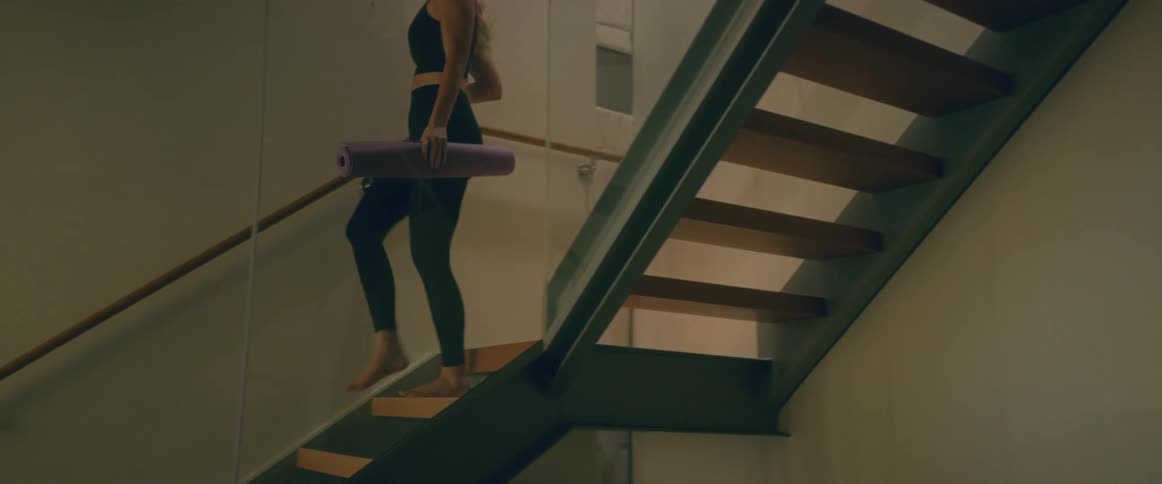 A woman walking down stairs with a yoga mat