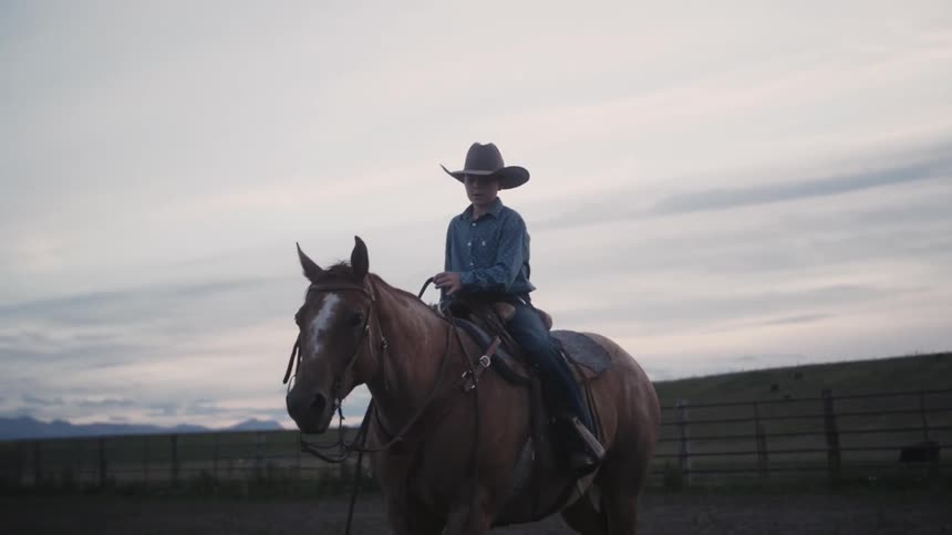 A boy is riding a horse in a ranch